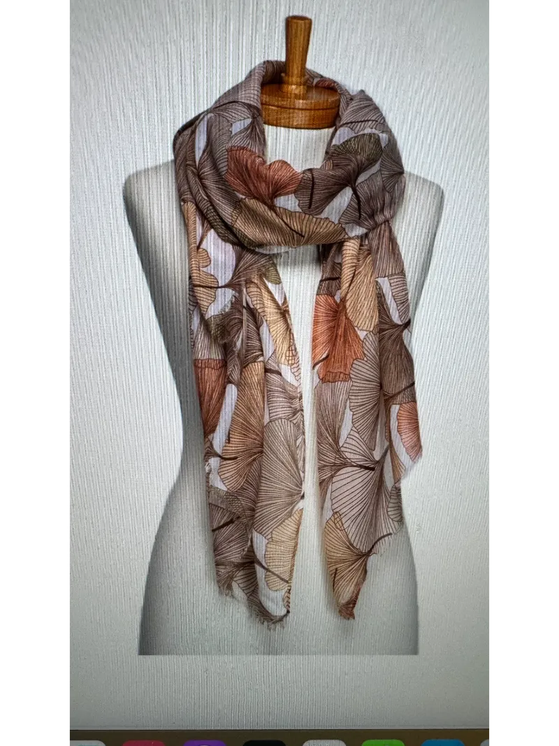 A scarf on a mannequin body tied in a front knot with a gingko leaf pattern in pastel apricot , beige and the softest green colours