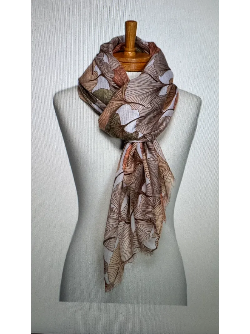 A scarf on a mannequin body tied in a twist knot with a gingko leaf pattern in pastel apricot , beige and the softest green colours