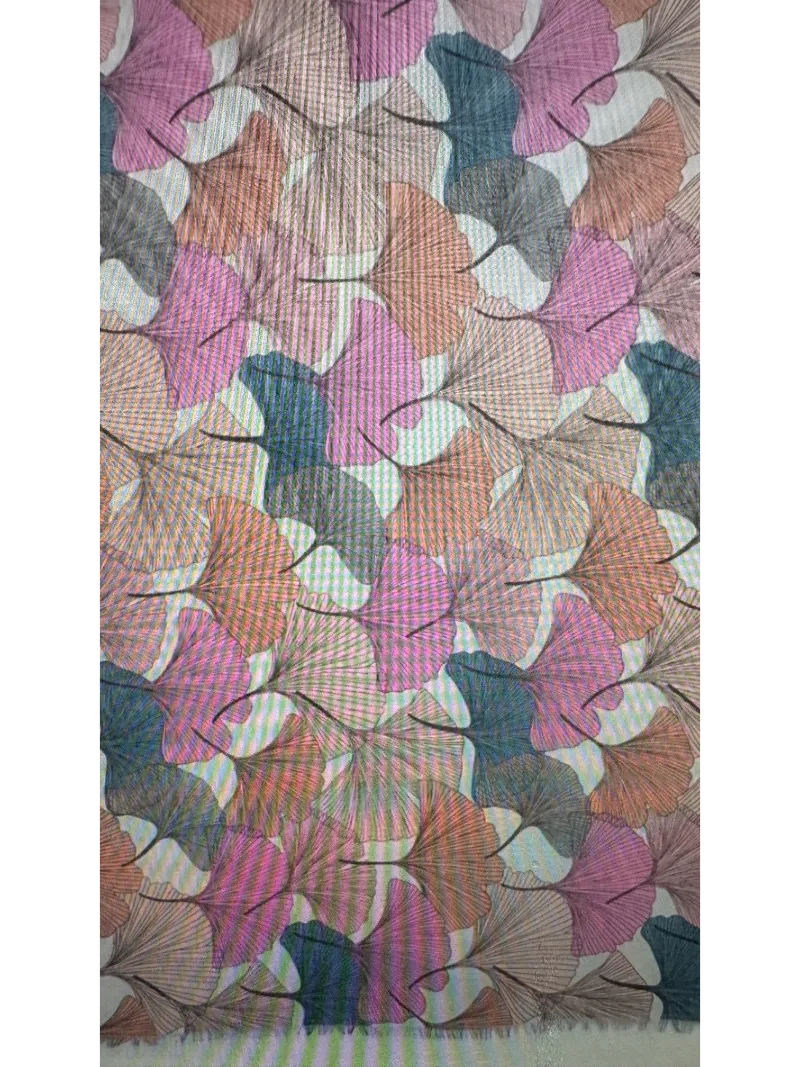 A close look at the pattern of a scarf with a gingko leaf design in pink,peach and blue colours