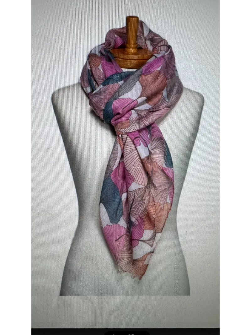 A scarf on a mannequin body tied in a twist knot with a gingko leaf pattern in pink,peach and blue colours
