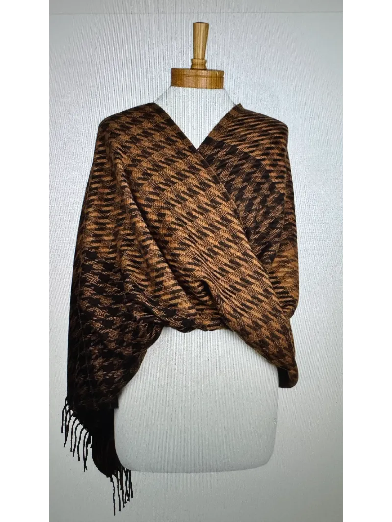 A cosy brown and black houndstooth scarf with a fringe worn as a wrap on a mannequin body