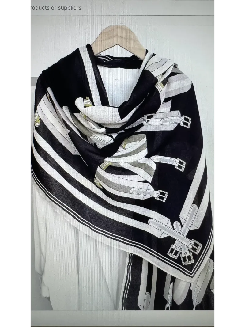 A black , cream and silver scarf with images of belts on a mannequin body draped as a wrap
