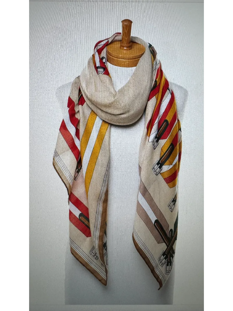 A scarf with a camel base featuring colours of tan red and green on a mannequin body tied in a front knot ,images of belts