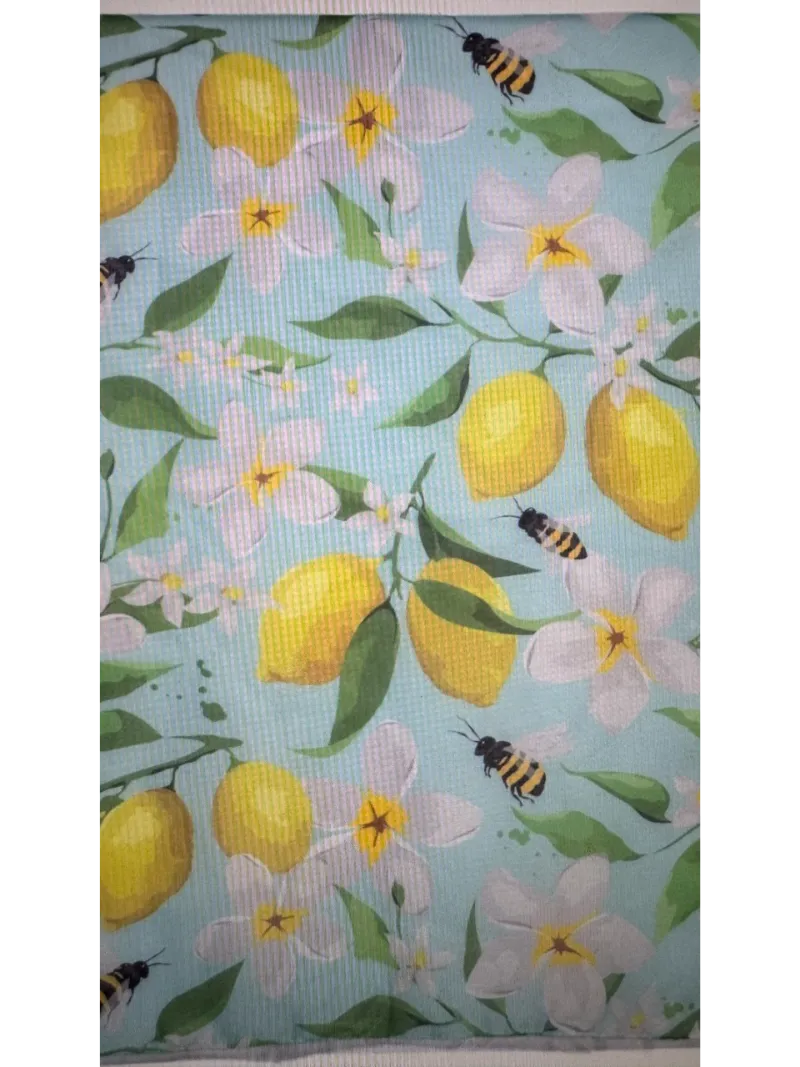 A close up of the pattern for the Scarf ,with images of bees and lemons and an aqua base