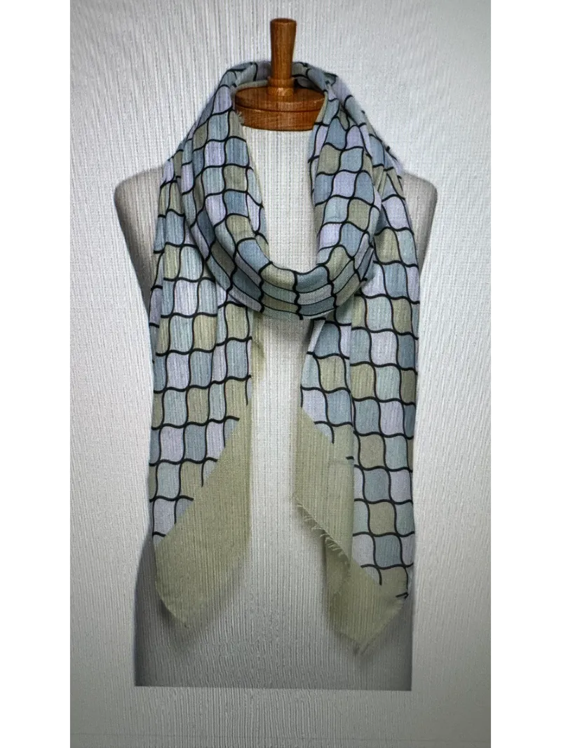 A scarf on a mannequin body tied in a front knot with a mosaic pattern in soft lime green , aqua and white